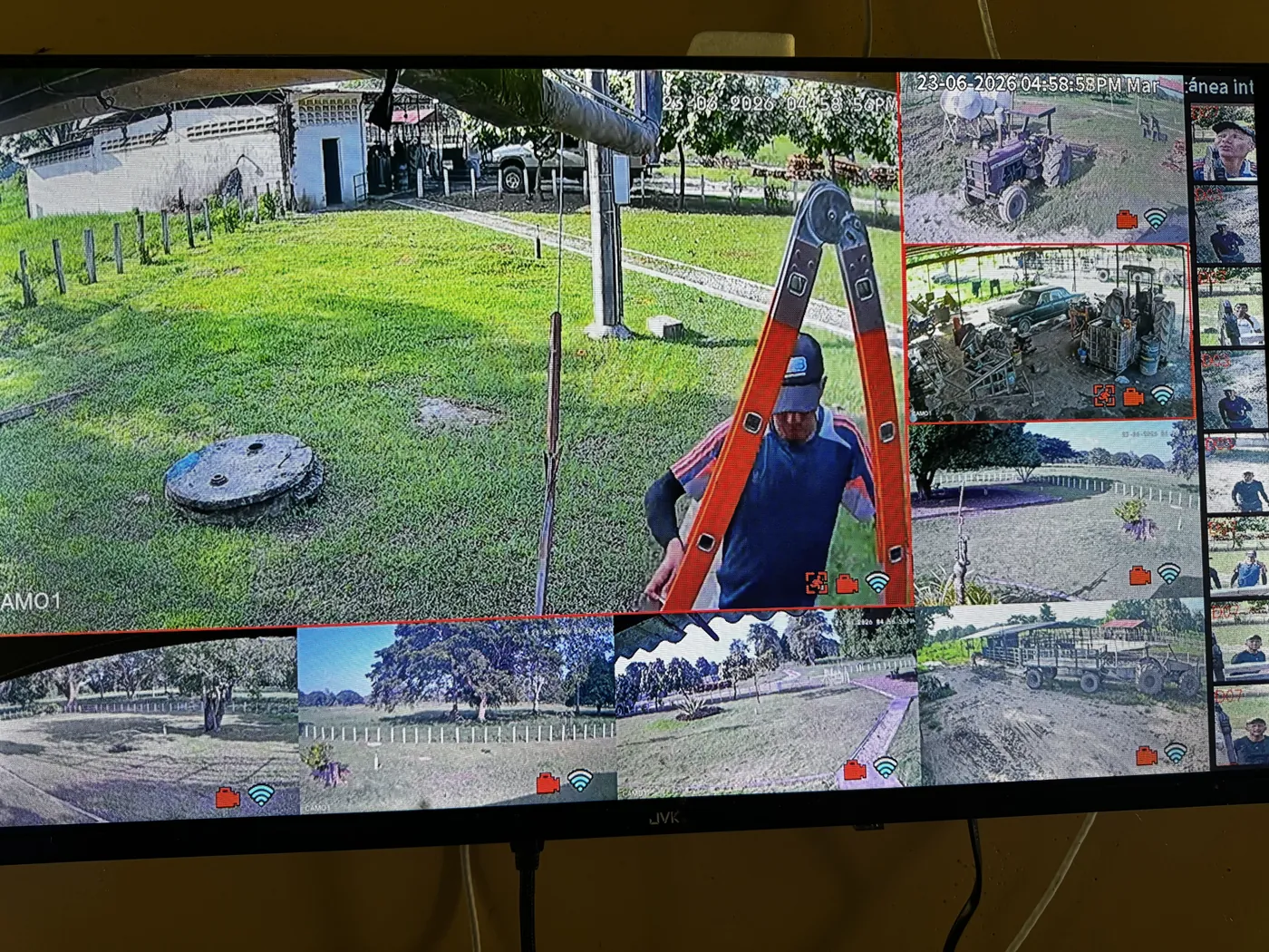 Técnico en una escalera en una finca, frente a la pantalla de monitoreo de las cámaras