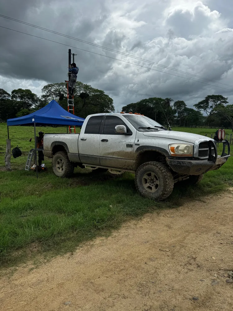 Técnicos de VSB instalando una cámara en un poste junto a su camioneta en una finca