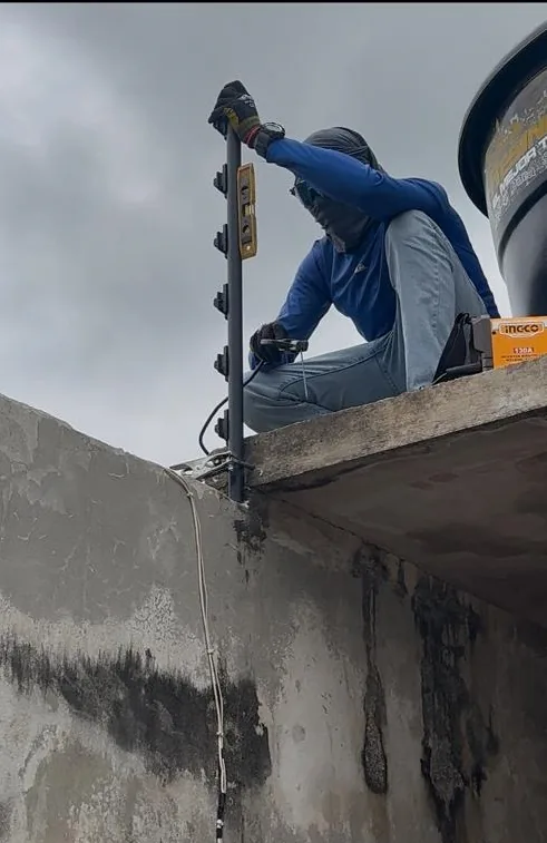Técnico instalando un cerco eléctrico sobre un muro